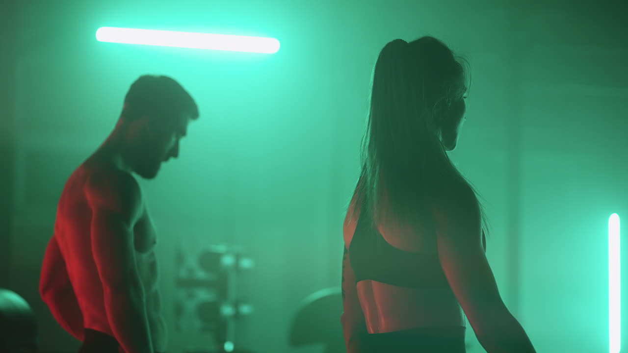 спортивный мужчина и женщина гуляют в темном тренажерном зале после тренировки активные люди держат себя в форме