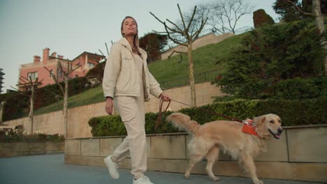 a young blonde girl in light clothes walks with her light-colored dog on the embankment in nature. morning walk with pet