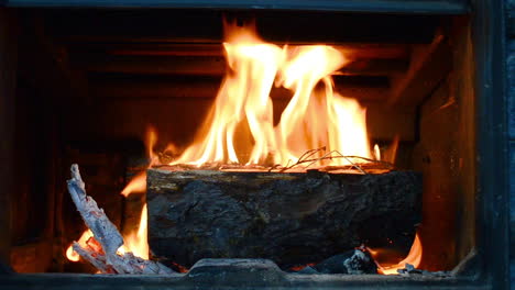 un borroso desenfocado a enfocado de un tronco en llamas en una chimenea de estufa de leña