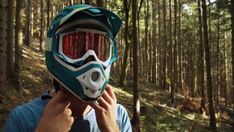 medium shot, downhill biker is wearing a blue full face helmet, trees in the background