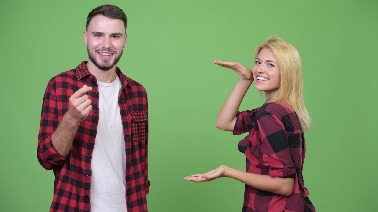 Young happy couple snapping fingers and showing something together