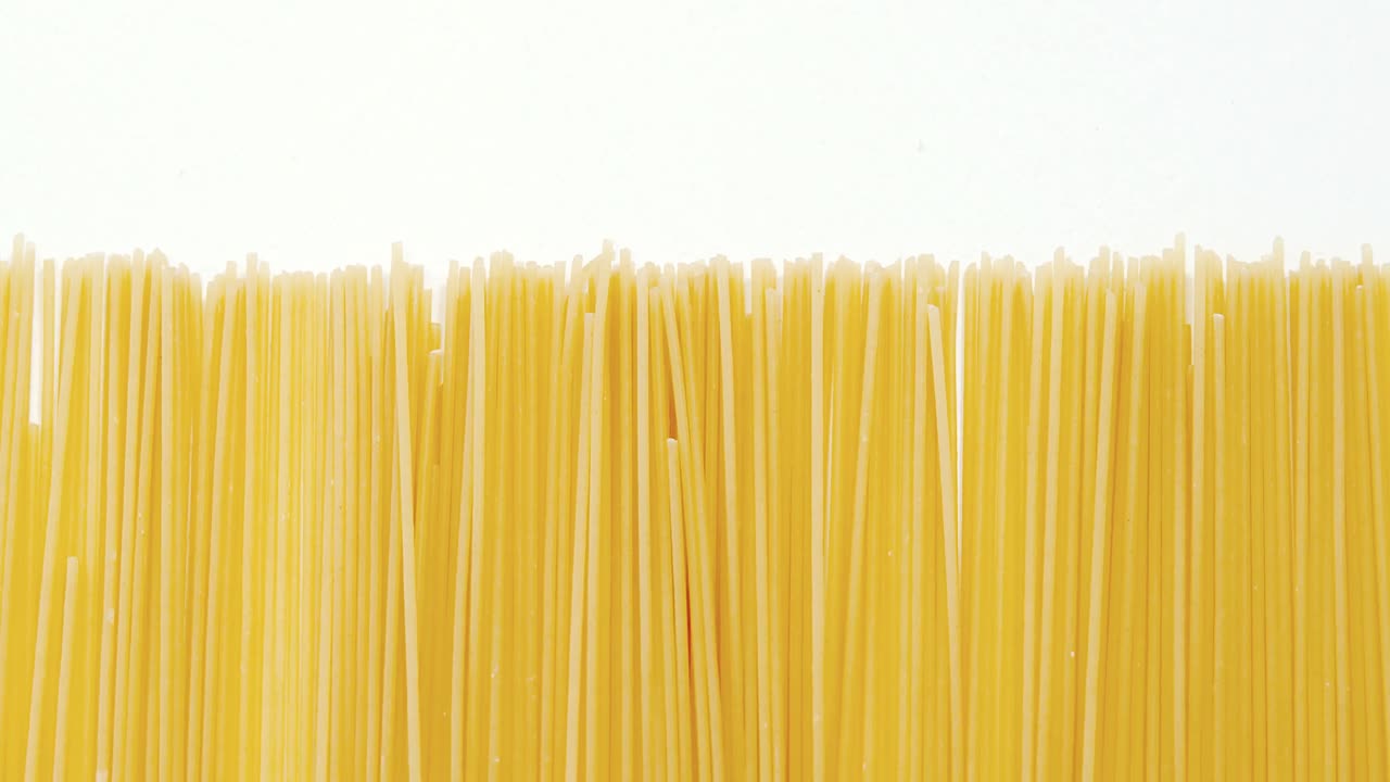 Raw spaghetti arranged on white background