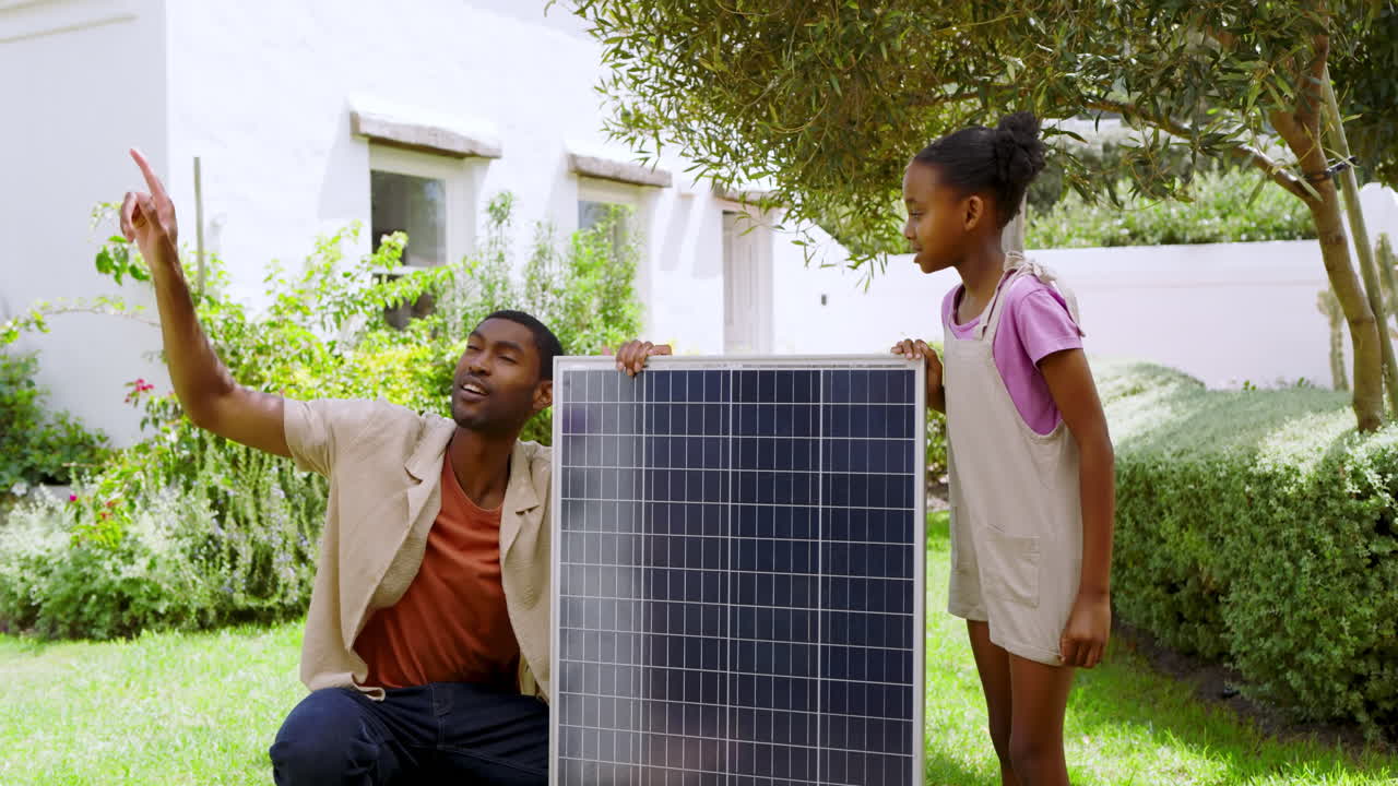 Installing solar panel in garden, african american father and child learning about renewable energy