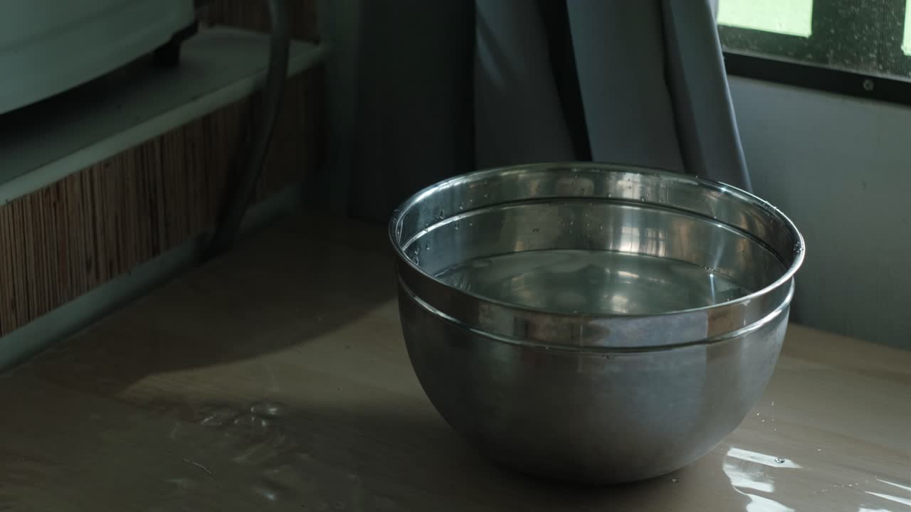 hände, die hartgekochte eier mit zangen in eine schüssel mit eiskaltem wasser legen.