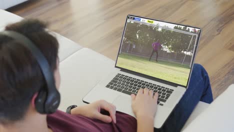 Video-Einer-Person,-Die-Auf-Der-Couch-Sitzt-Und-Sich-Ein-Fußballspiel-Auf-Dem-Laptop-Ansieht