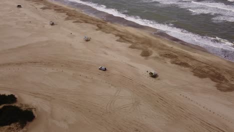 vista aérea de la conducción de vehículos de cuatro ruedas en la playa de arena durante el día soleado en verano, tiro de seguimiento