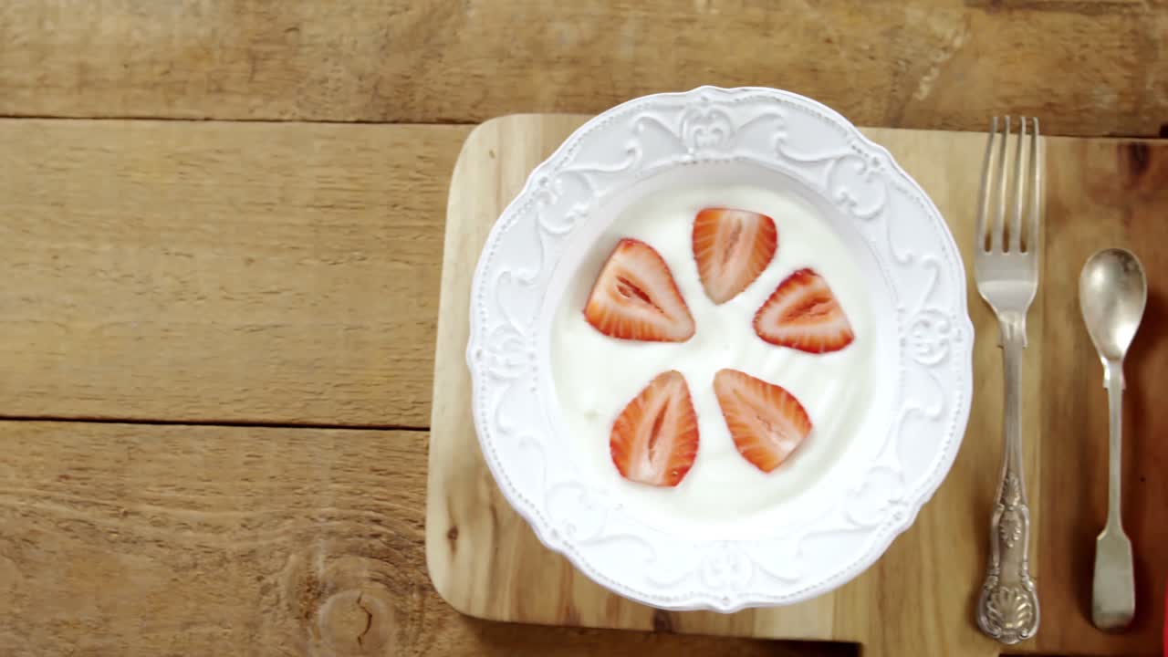 Slices of strawberries in plate with spoon