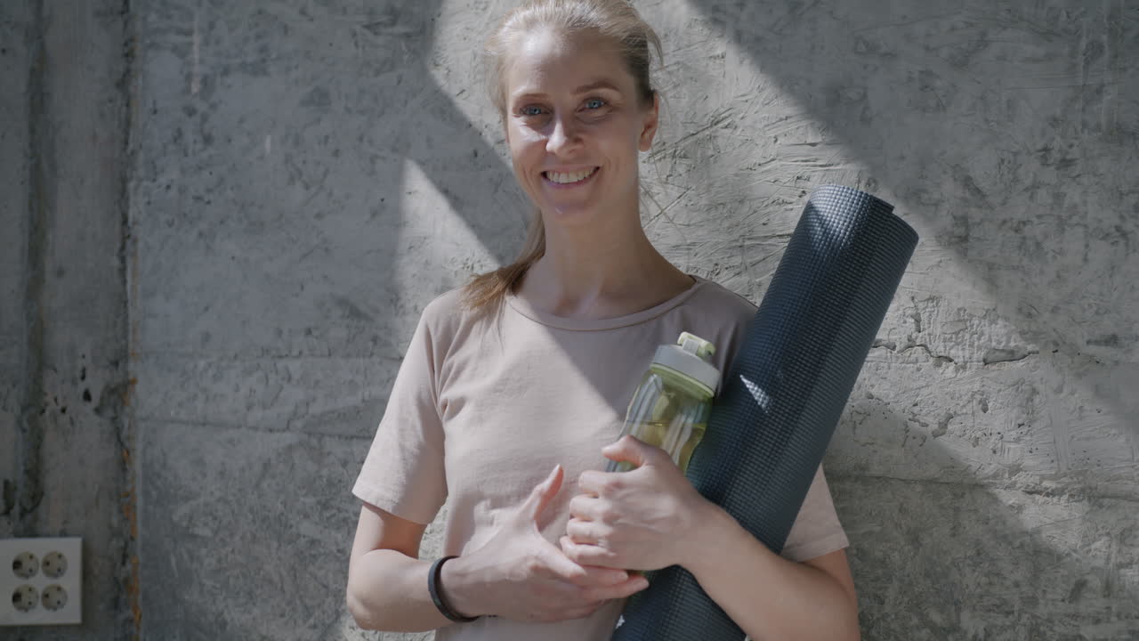 Smiling Woman with Yoga Mat and Water Bottle