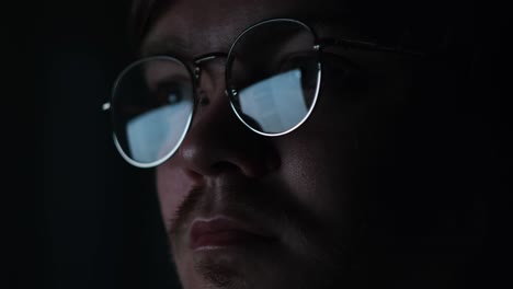 close-up of a person wearing glasses in the dark