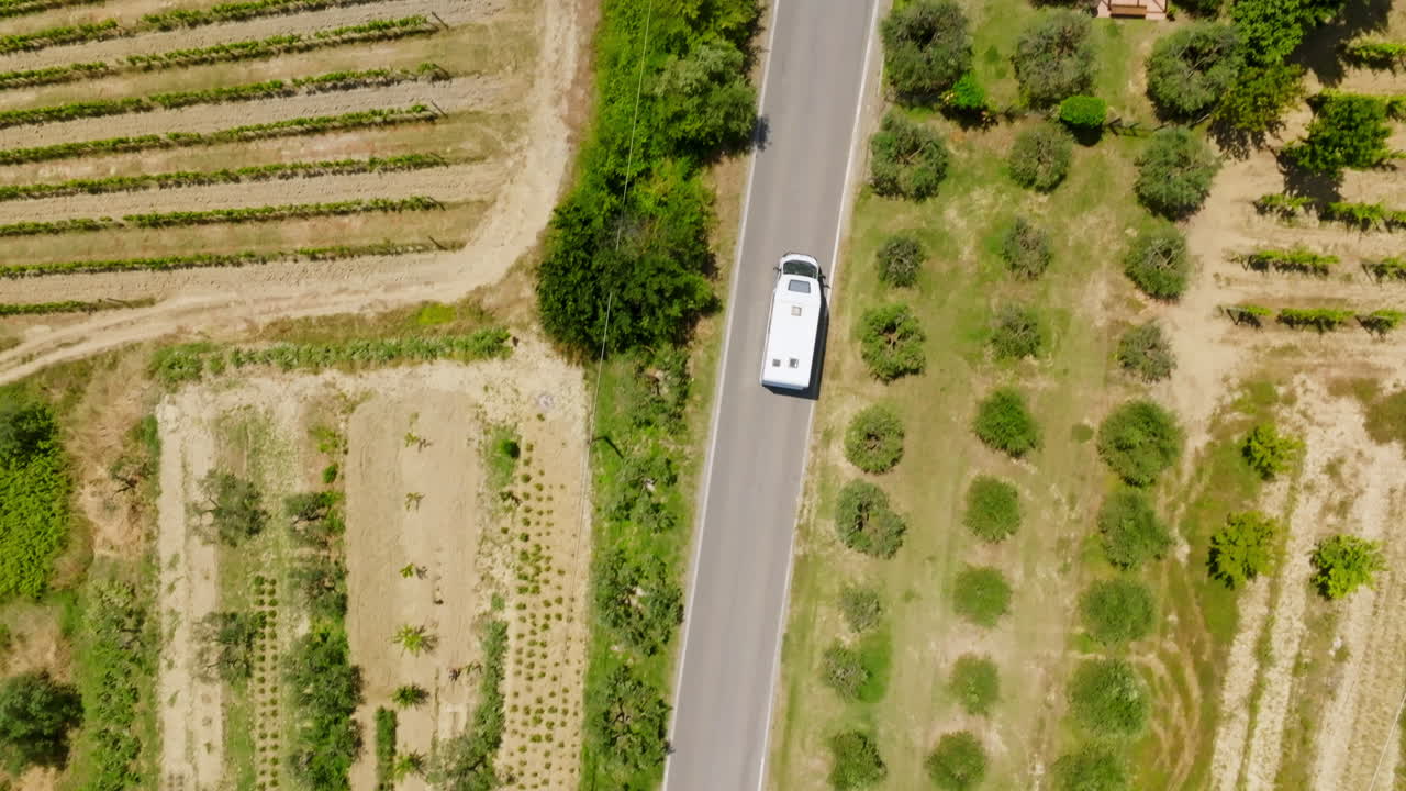 Top down drone shot above a Camper van driving in middle of vineyards of Italy