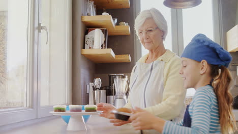 abuela feliz y una niña pequeña colocando muffins en el mostrador de la cocina 4k 4k