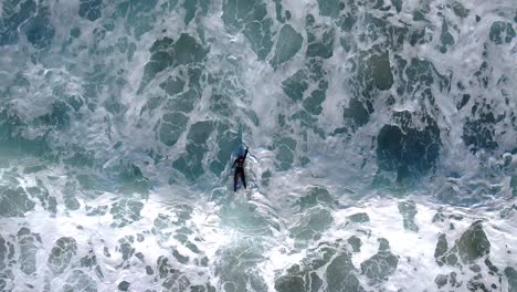 a determined surfer paddles out to sea against some strong waves