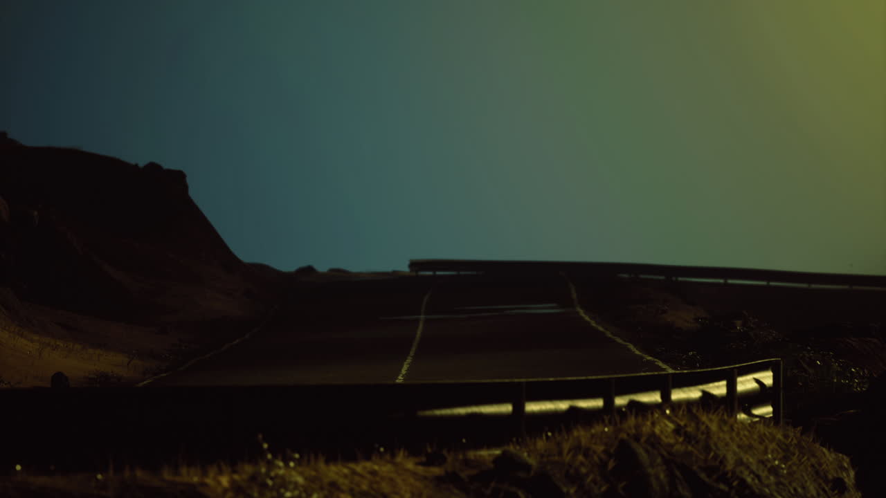 Winding mountain road illuminated by moonlight at dusk