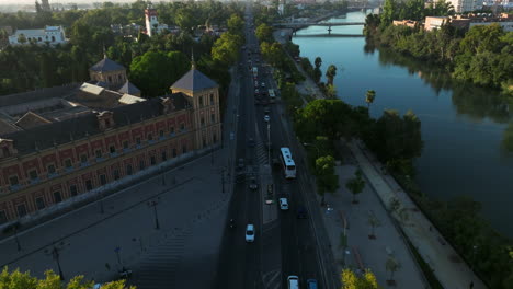 tráfico temprano en la mañana pasando por el palacio de san telmo a lo largo del río en sevilla, españa