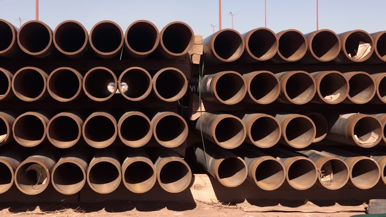 Tubi industriali impilati alla luce del sole, a simboleggiare costruzione e utilità