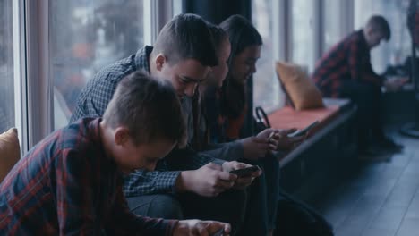 teenagers using smartphones in a cafe