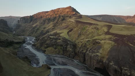 aerial view of a rugged canyon and winding river in northern iceland, showcasing steep volcanic cliffs and dramatic landscapes under a serene sky.