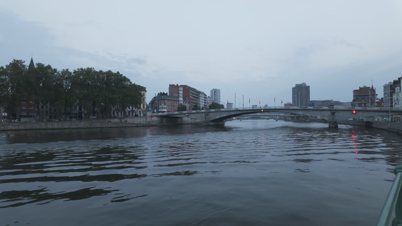 벨기에의 리에지 (liège) 에서 저녁에 지나가는 보트와 현대적인 다리와 함께 평온한 강