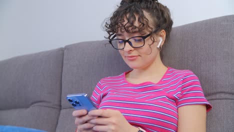 mujer escuchando música y escribiendo mensajes en el teléfono móvil. mujer alegre comunicándose en línea en la aplicación de redes sociales en un teléfono inteligente moderno y disfrutando de sus pistas musicales favoritas con auriculares inalámbricos
