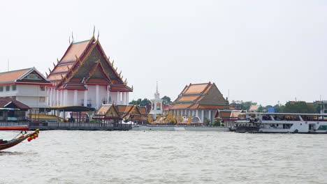 longboat travels past temple on bangkok river