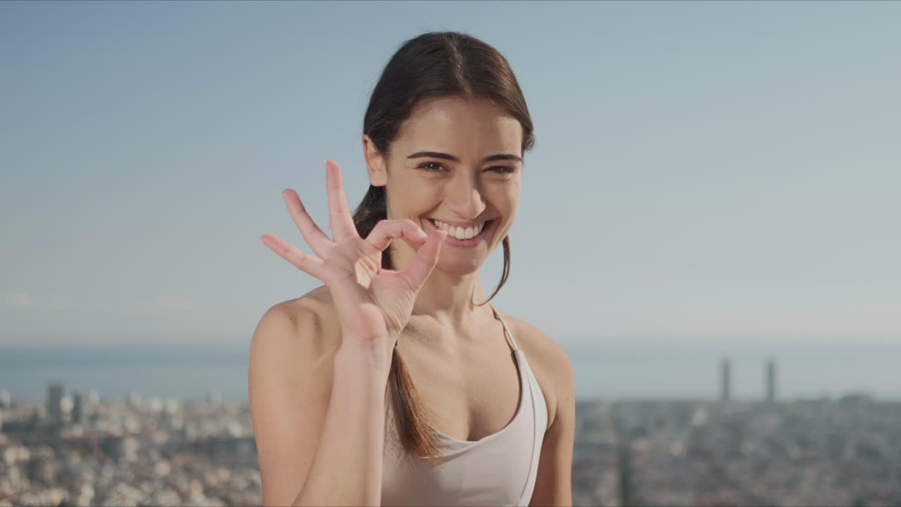 mujer mostrando un letrero de ok después de un entrenamiento de yoga en la calle. niña posando para la cámara