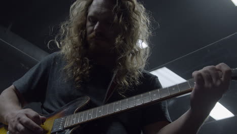 rock musician with long hair playing guitar in professional recording studio (cinematic slow motion)