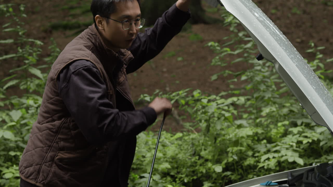Man inspecting car engine in outdoors