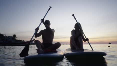 couple paddleboarding at sunset
