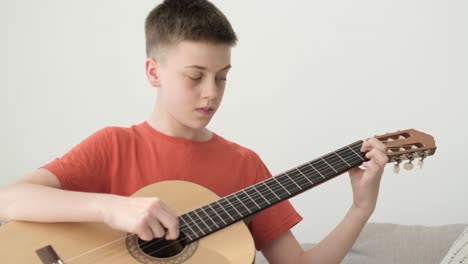 teacher instructing teenage boy playing guitar, music lesson at home.