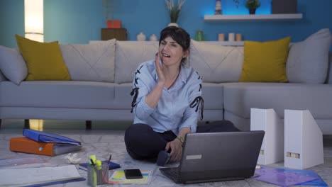 una mujer que trabaja en una oficina en casa tiene sensibilidad dental.