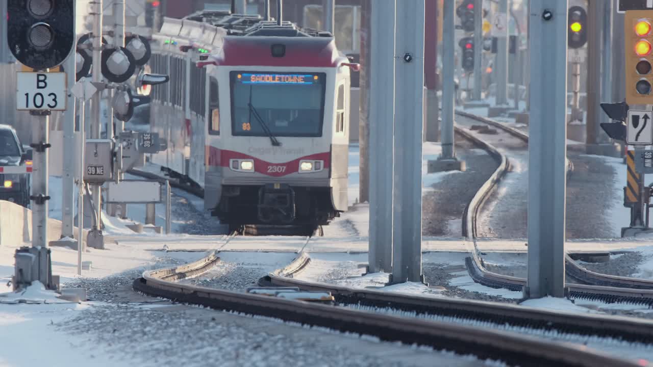 Calgary Transit train on winding icy tracks kicks up snow as it passes