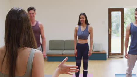 Caucasian-female-yoga-instructor-talking-to-happy-diverse-group-during-yoga-class-at-studio