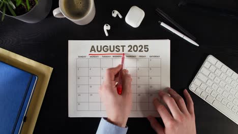 person looking at august 2025 calendar on a desk