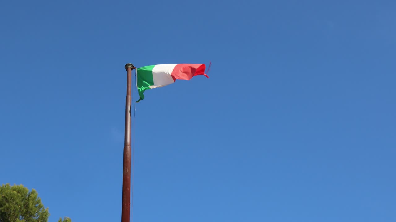Bandiera italiana che sventola al vento - cielo blu soleggiato sullo sfondo.