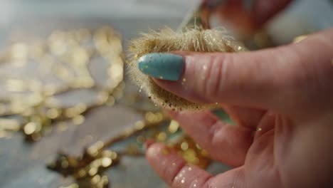 woman crafting with gold glitter and pom-poms