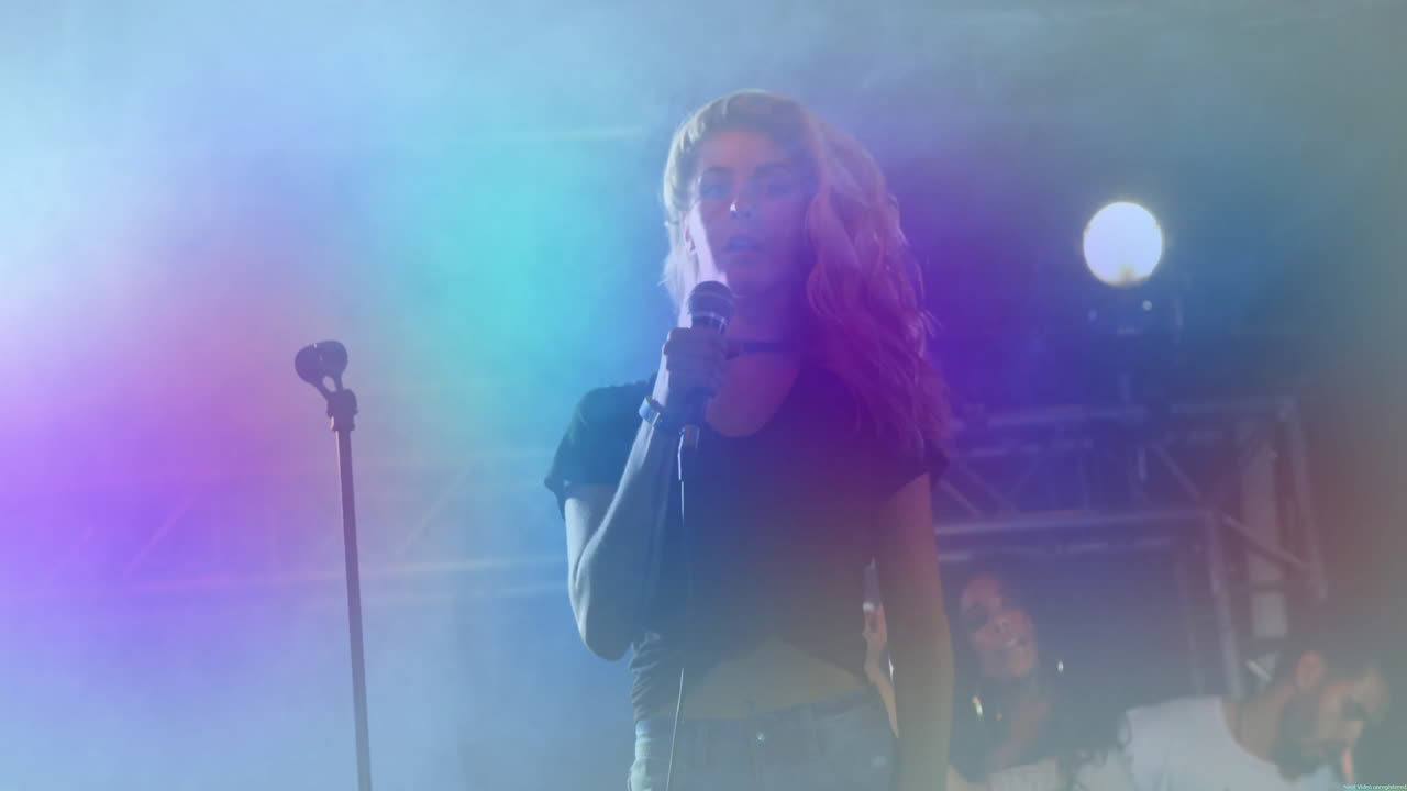 Cantante solista donna che si esibisce su un palco musicale, con un'icona animata di asta microfono e fasci di nebbia colorati.