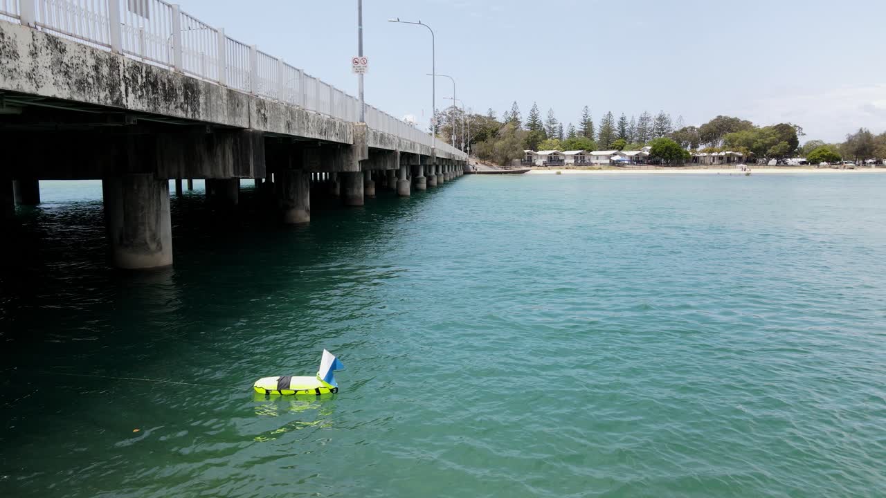 스쿠버 다이버 의 안전 보이 와 발 이 해안 도시 다리  에 있는 물 위 에 떠 있다