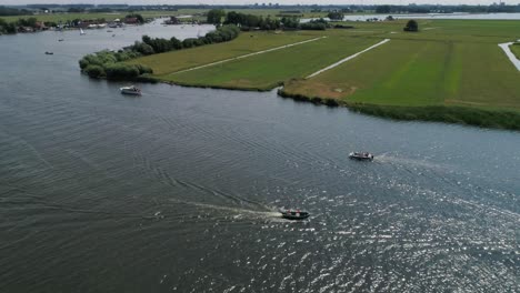 slomo aéreo panoramización alrededor de un bote pequeño con 5 amigos varones navegando rodeado de otros botes campo holandés durante el clima cálido