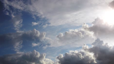 blazing-sun-behind-the-clouds,-blue-sky