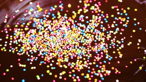 colorful sprinkles scattered over a chocolate surface