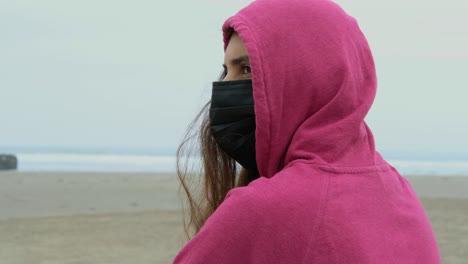 chica en la playa con mascarilla vista posterior