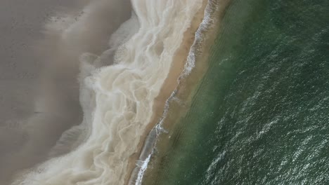 Atlantic-waves-crash-gently-on-sandy-shore-of-white-Icelandic-beach,-aerial