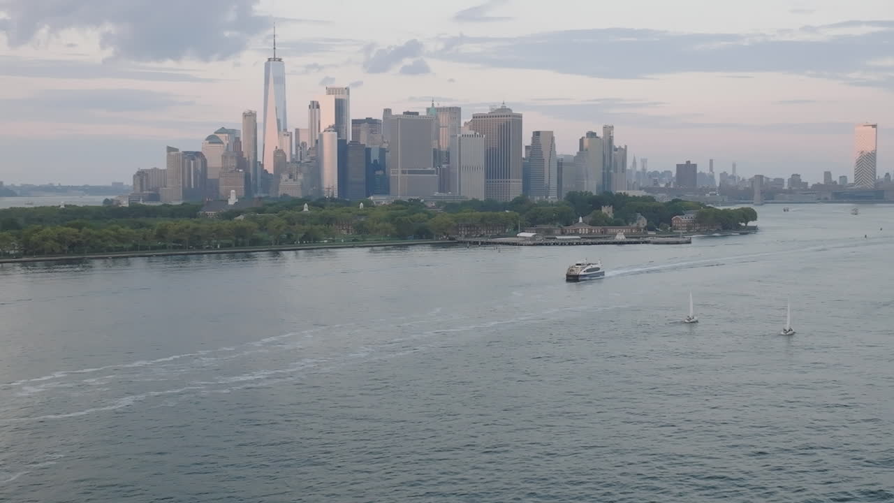 Shot at dusk with the World Trade Center, Governor's Island, and the Manhattan skyline in the background