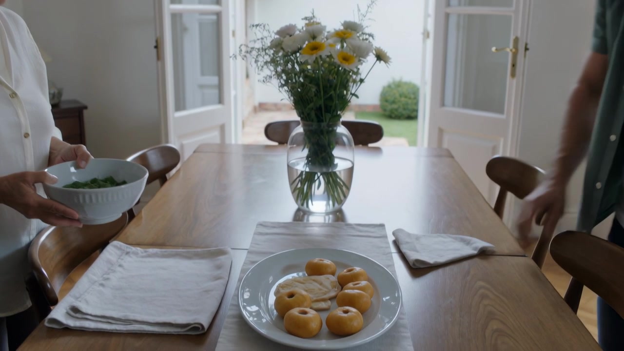 Preparing meal, senior woman in white top placing bowl on dining room table, man smoothing napkin