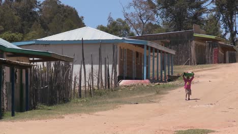 un niño pequeño lleva una bandeja de comida por un camino de tierra en el norte de kenia