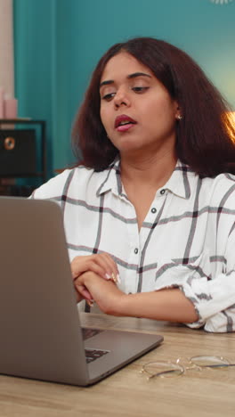 indian woman waving hand during video call on laptop smiling warm gesture to camera greeting online