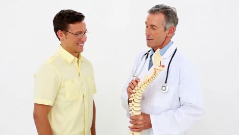 Doctor-holding-spine-model-talking-to-patient