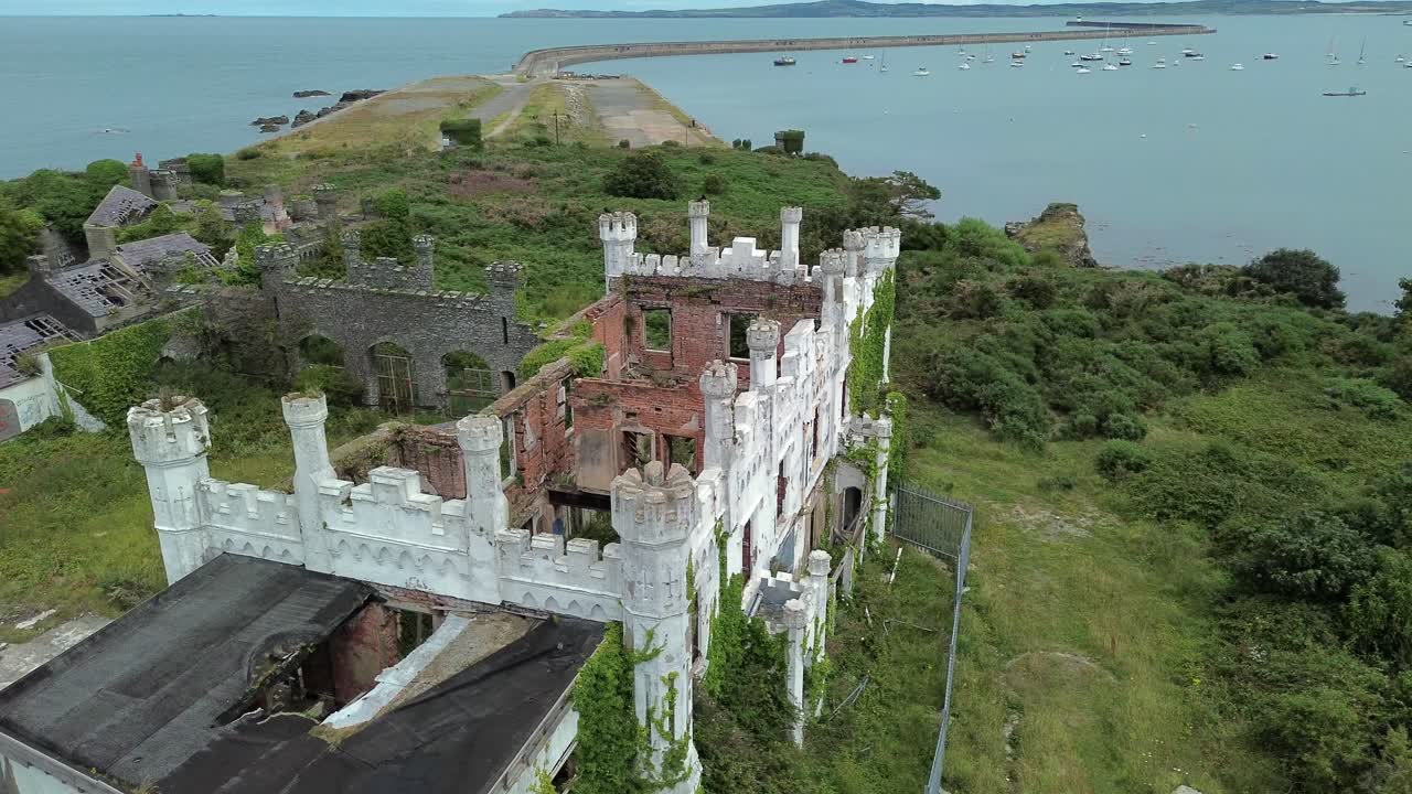 Uninhabited mental health hospital remains aerial view circling above overgrown North Wales landmark