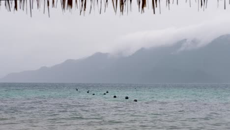ocean buoys bobbing in water on a wet, grey, cloudy and rainy day in remote tropical island destination