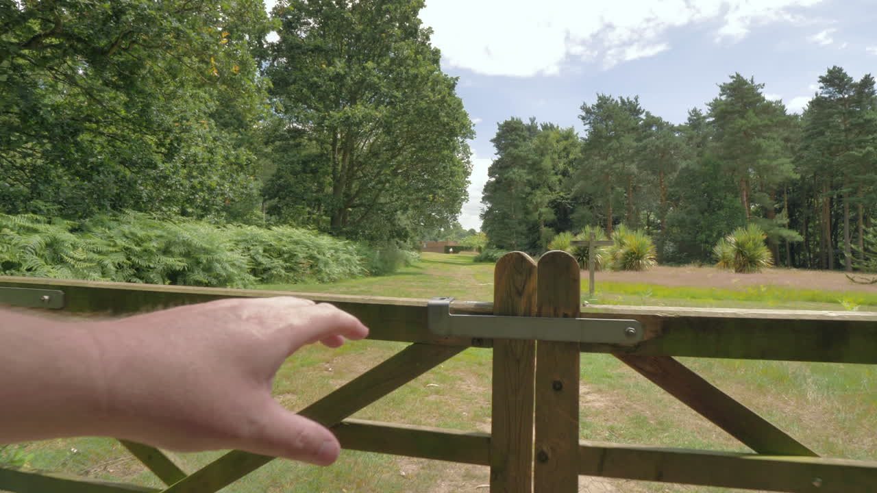 vista en primera persona de un hombre abriendo una puerta en un campo, mostrando árboles y el campo.